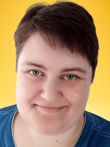 Portrait von Mim Gaisser, eine eher kunge Person mit kurzen, dunkelbraunen Haaren und einem blauen T-Shirt.