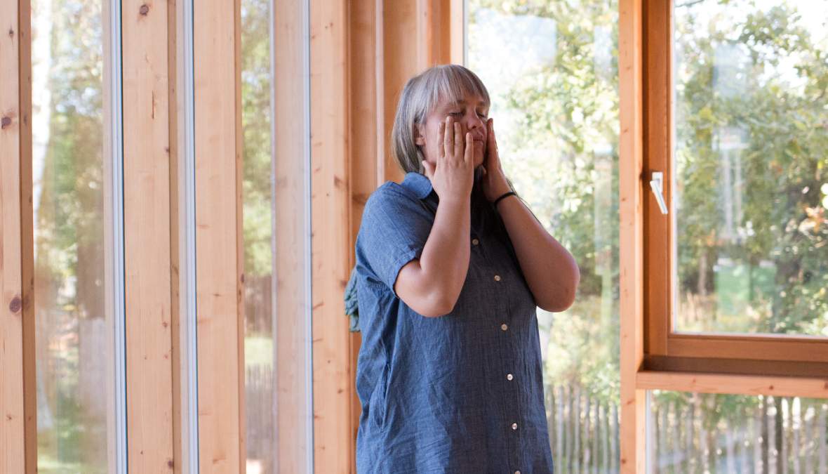 Kiefer lockern in 5 Schritten Paula bei einer der 5 Übungen für einen lockeren Kiefer: Sie hat beide Hände auf ihre Wangen gelegt und die Augen geschlossen.