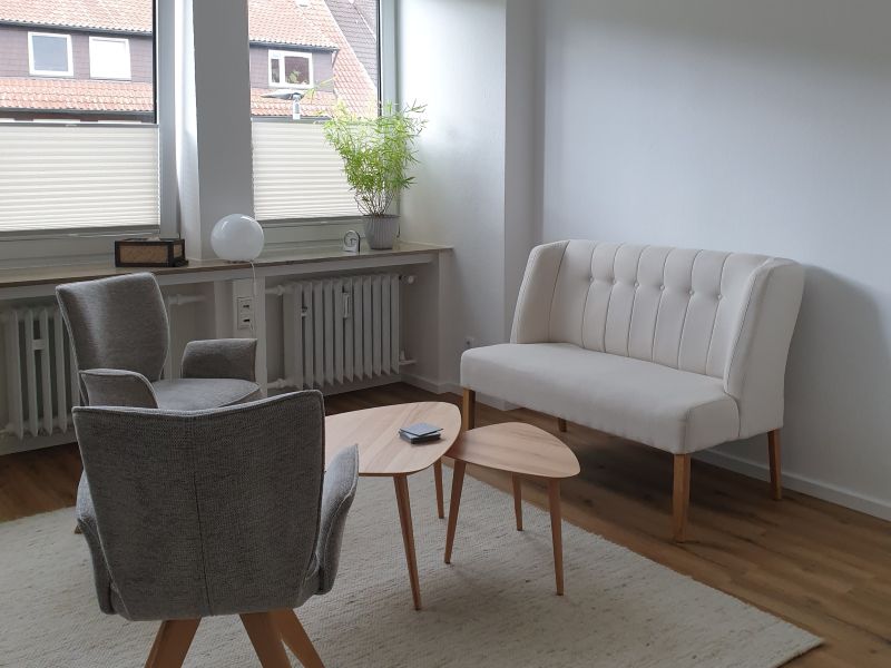 Ein Raum mit Sofa, Sesseln, Couchtisch und großen Fenstern.