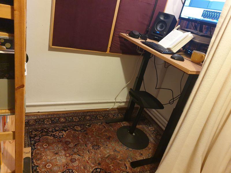 Der Teppich in Paulas Studio. Darauf steht ein Regal, ein Schreibtisch und ein Hocker.