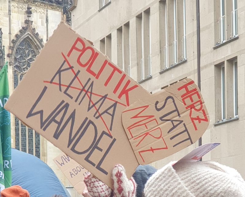 Schilder auf einer Demonstration. Darauf steht: "Politik- statt Klimawandel" und "Herz statt Merz".