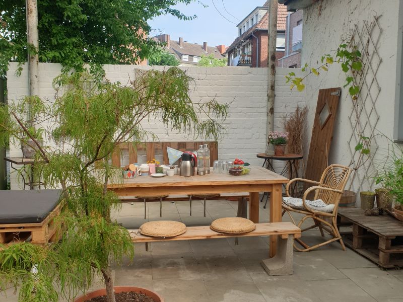 Ein Innenhof mit weißen Mauern, Pflanzen und einem gedekcten Tisch.