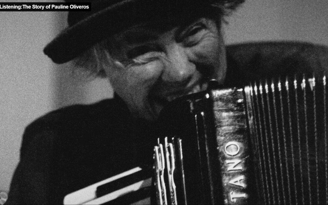 Pauline Oliveros, lachend, mit Hut und Akkordeon.