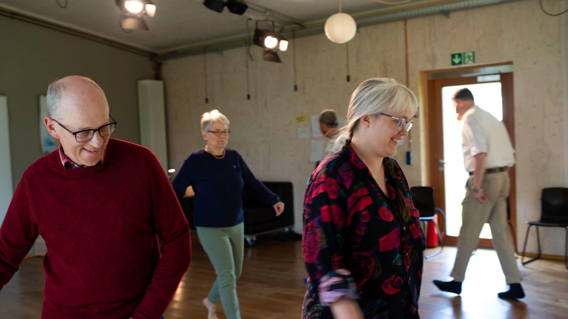 Workshops rund um Stimme, Sprechen, Kunst & Kommunikation Eine Szene aus einem Workshop: Paula und vier weitere Menschen gehen kreuz und quer durch einen Raum.