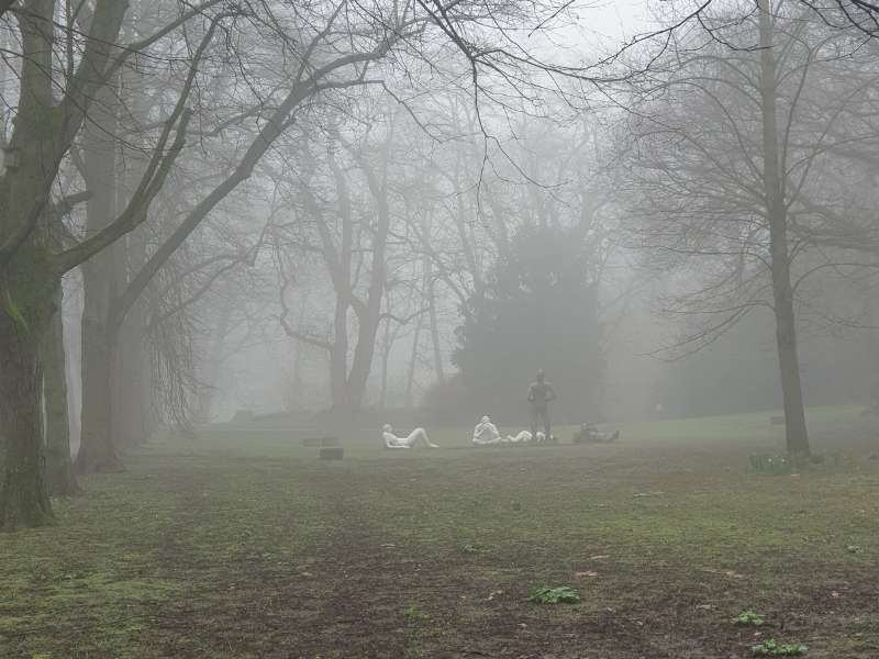 Ein Park mit Skulpturen im Nebel.